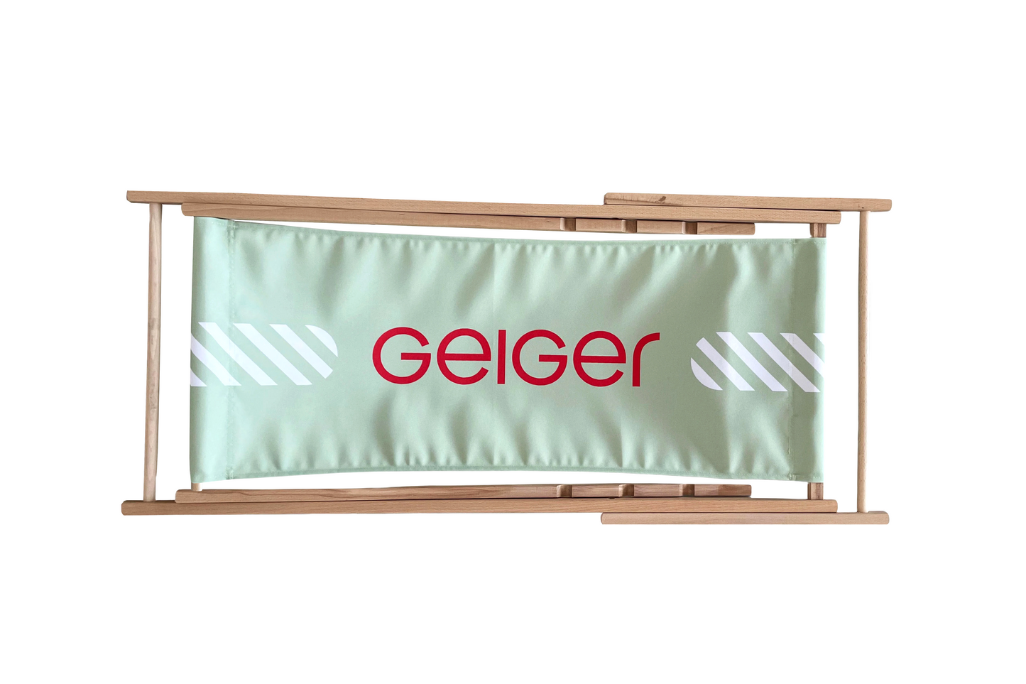 Liegestuhl aus Holz mit grünem Stoff mit roten "Geiger" Logo und weißen Gesaltungselementen. Liegestuhl ist auf 3 Stufen einstellbar.