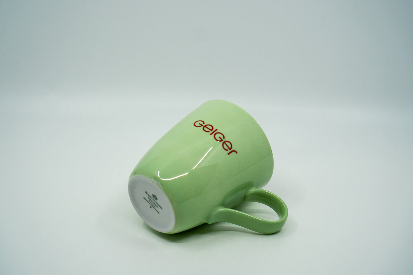 Geiger-Grüne Porzellantasse mit rotem "Geiger" Schriftzug.