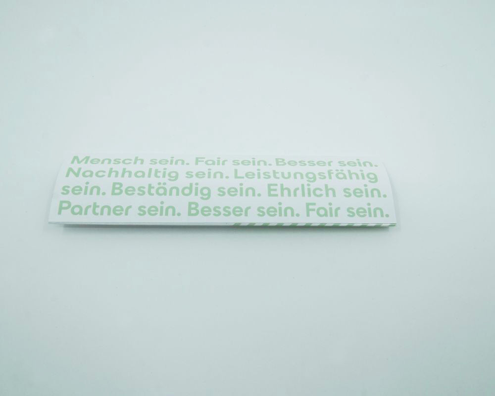 Geiger Druckbleistift in Geiger-Grün mit roter Klammer, Knopf und Spitze. Auf dem Stift ist ein "Geiger" Schriftzug. Papierverpackung im Geiger Design inklusive.