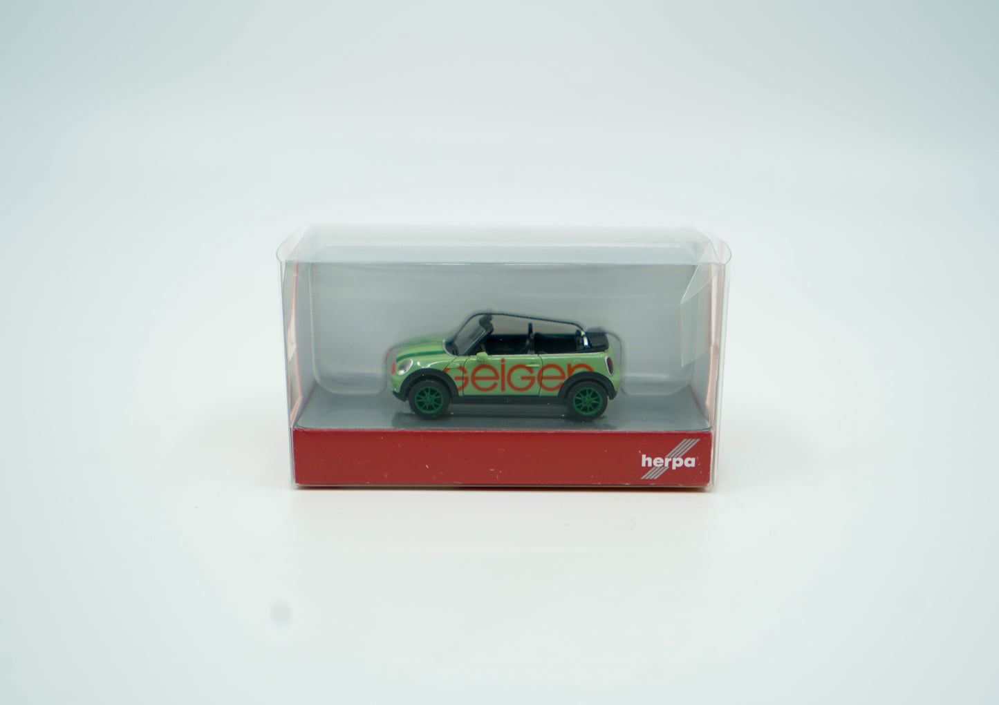 Miniaturmodell eines Geiger Mini-Cooper PKW in Geiger-Grün mit rotem „Geiger“-Schriftzug, Verpackung inklusive.
