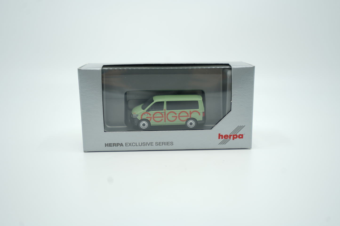 Miniaturmodell eines Geiger VW-Bus in Geiger-Grün mit rotem „Geiger“-Schriftzug, Verpackung inklusive.