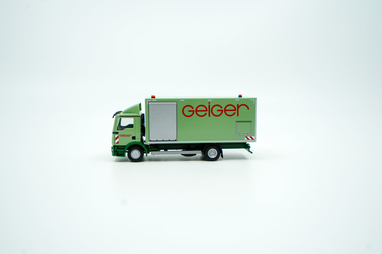 Miniaturmodell eines MAN Geiger-LKW mit geschlossenem Kastenaufbau in Geiger-Grün und rotem "Geiger" Schriftzug. Verpackung inklusive.