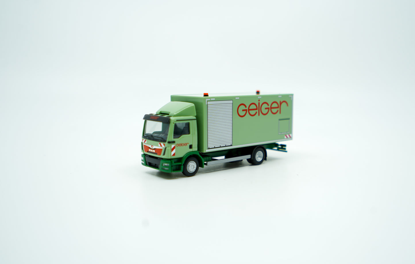 Miniaturmodell eines MAN Geiger-LKW mit geschlossenem Kastenaufbau in Geiger-Grün und rotem "Geiger" Schriftzug. Verpackung inklusive.