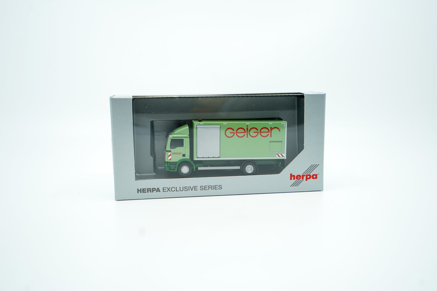Miniaturmodell eines MAN Geiger-LKW mit geschlossenem Kastenaufbau in Geiger-Grün und rotem "Geiger" Schriftzug. Verpackung inklusive.