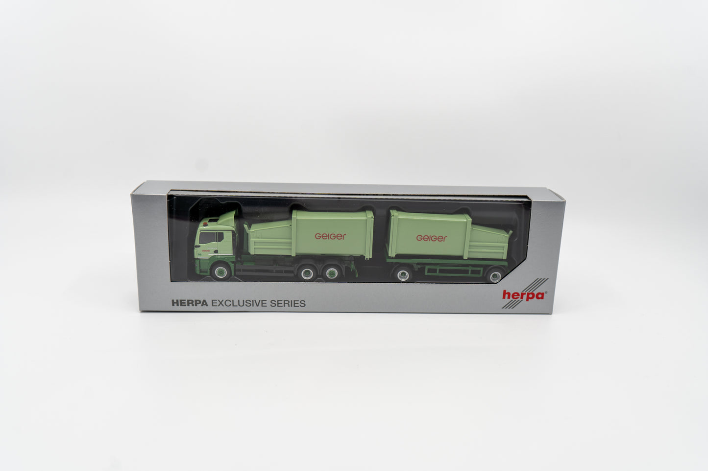 Miniaturmodell eines MAN Geiger-LKW mit Pressmüllcontainer Aufbau in Geiger-Grün mit rotem "Geiger" Schriftzug. Verpackung inklusive.