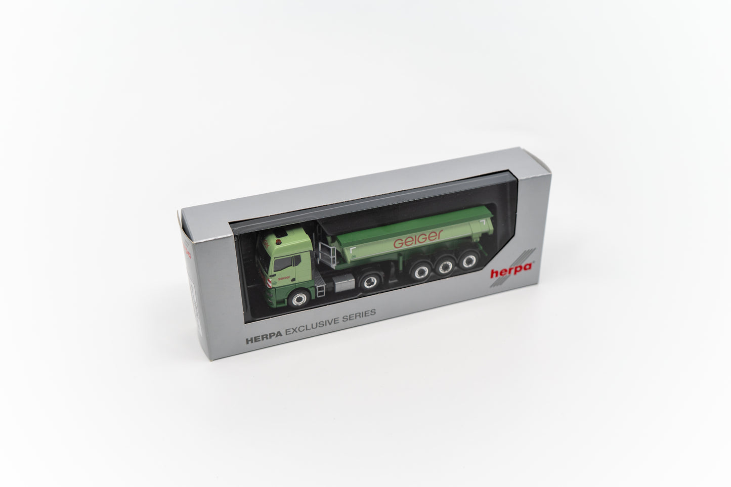 Miniaturmodell eines Geiger MAN TGX GM Thermomulden-Sattelzug in Geiger-Grün mit rotem „Geiger“-Schriftzug.