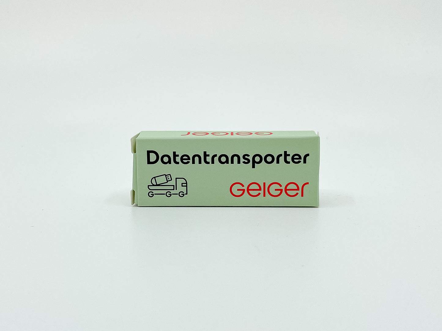 USB-Stick in Geiger-Grün mit rotem „Geiger“-Schriftzug, präsentiert mit passender Verpackung in Geiger-Grün und der Aufschrift „Datentransporter“.