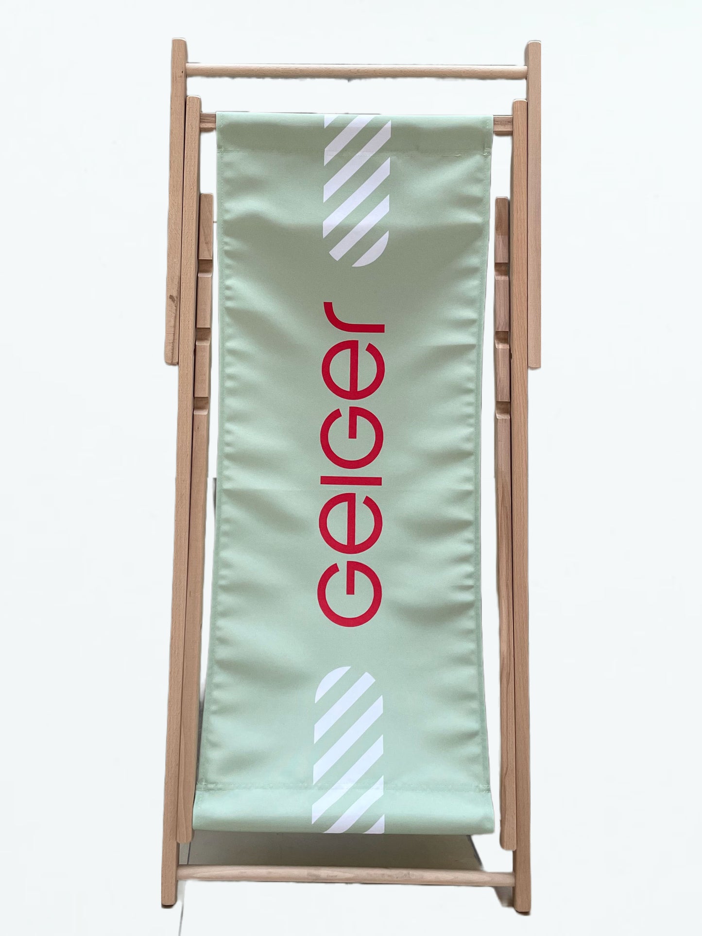 Liegestuhl mit einem Holzgestell und einem Stoffbezug in Geiger-Grün mit rotem „Geiger“-Schriftzug.