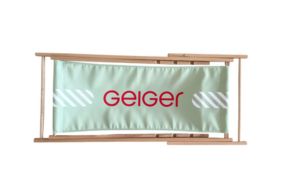 Liegestuhl aus Holz mit grünem Stoff mit roten "Geiger" Logo und weißen Gesaltungselementen. Liegestuhl ist auf 3 Stufen einstellbar.