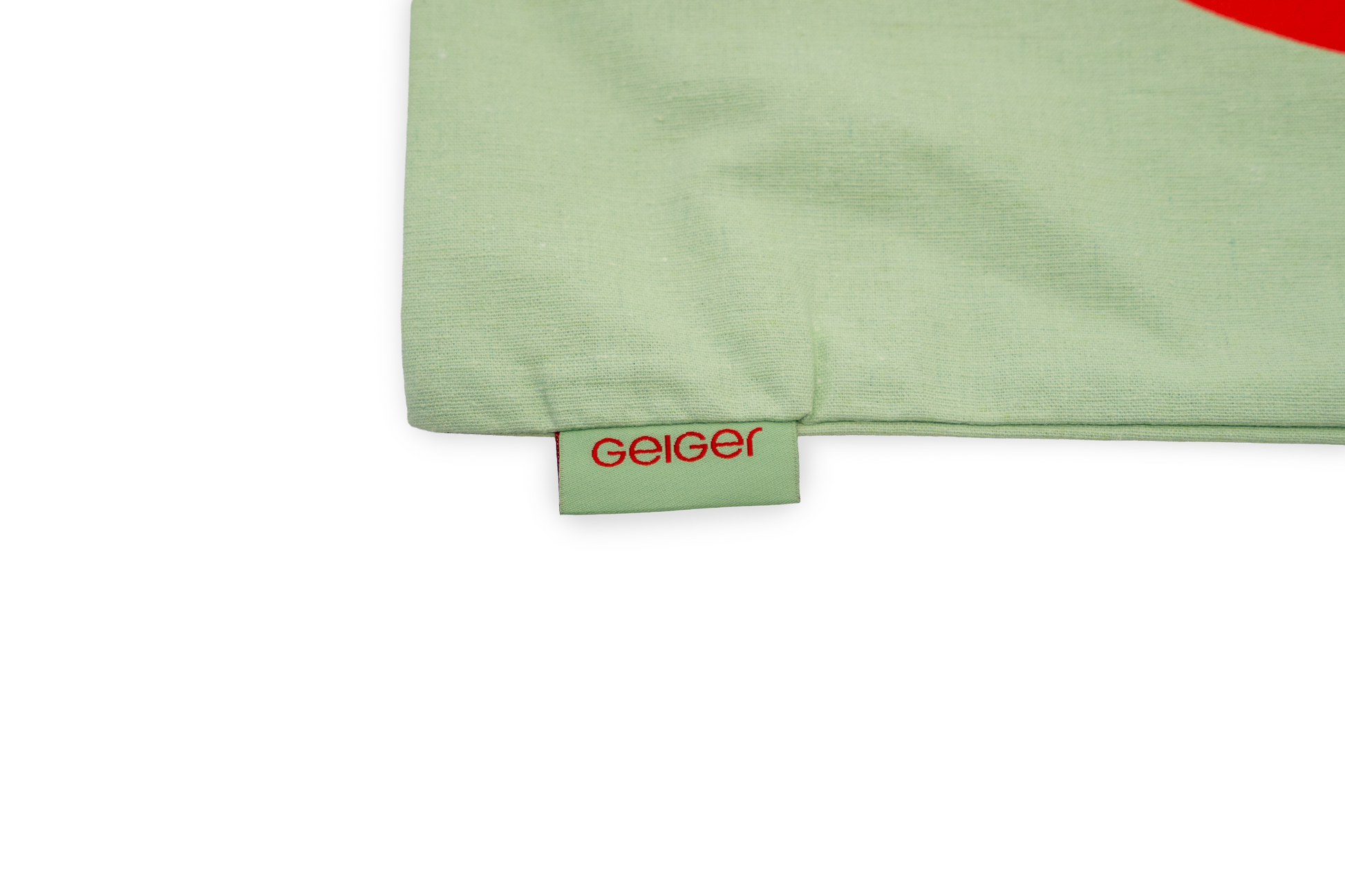 Stofftasche in Geiger-Grün mit einem großen roten „G“ auf der Vorder- und Rückseite und zwei Tragehenkeln.