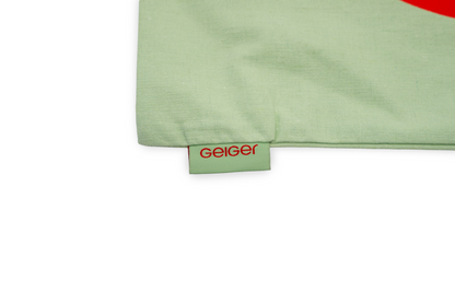 Stofftasche in Geiger-Grün mit einem großen roten „G“ auf der Vorder- und Rückseite und zwei Tragehenkeln.