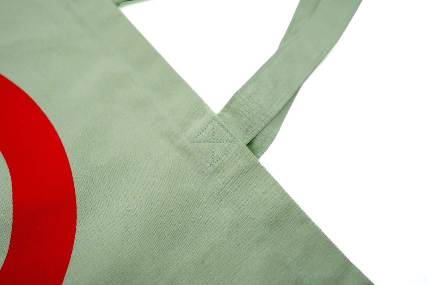 Stofftasche in Geiger-Grün mit einem großen roten „G“ auf der Vorder- und Rückseite und zwei Tragehenkeln.