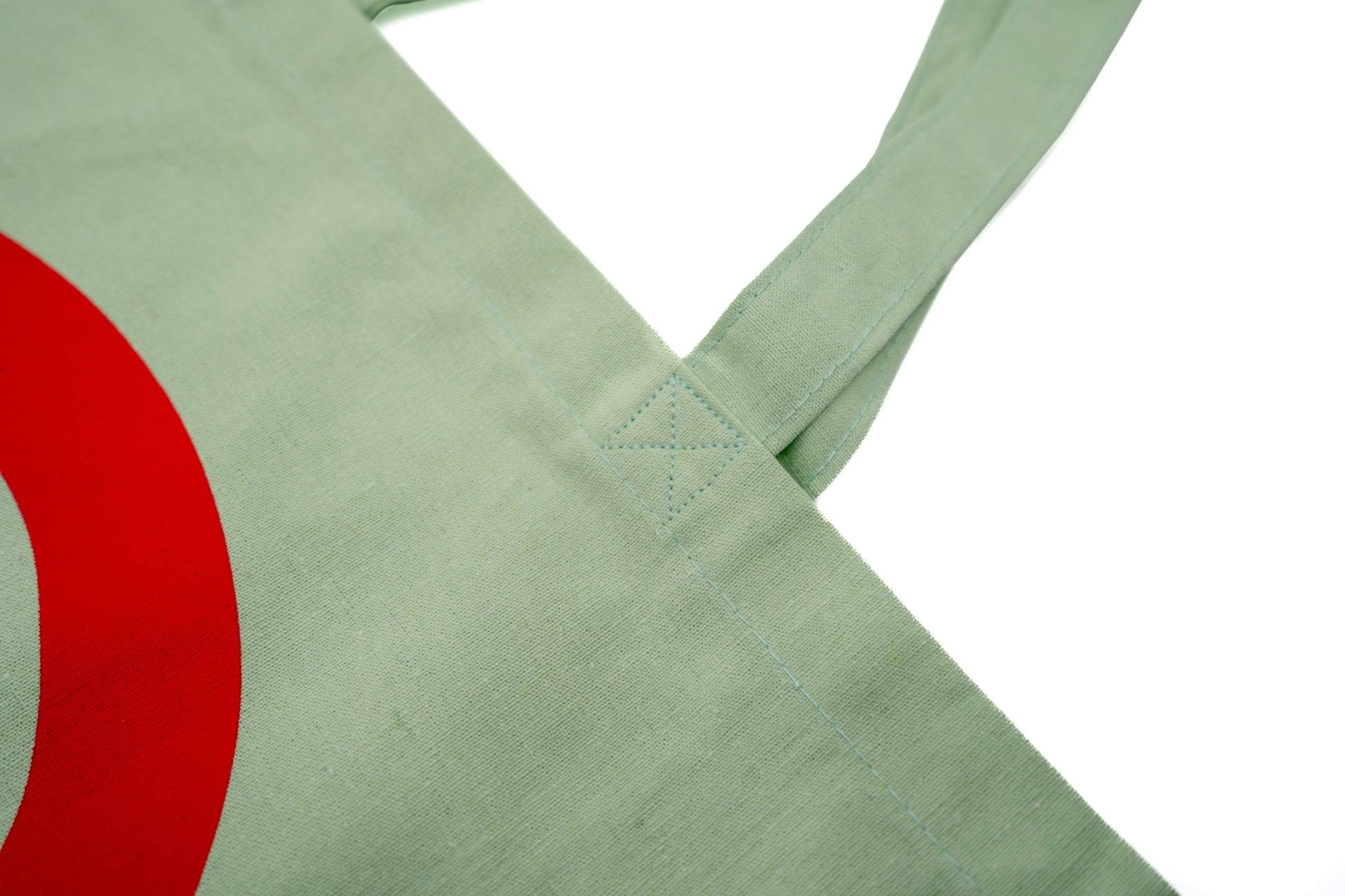 Stofftasche in Geiger-Grün mit einem großen roten „G“ auf der Vorder- und Rückseite und zwei Tragehenkeln.