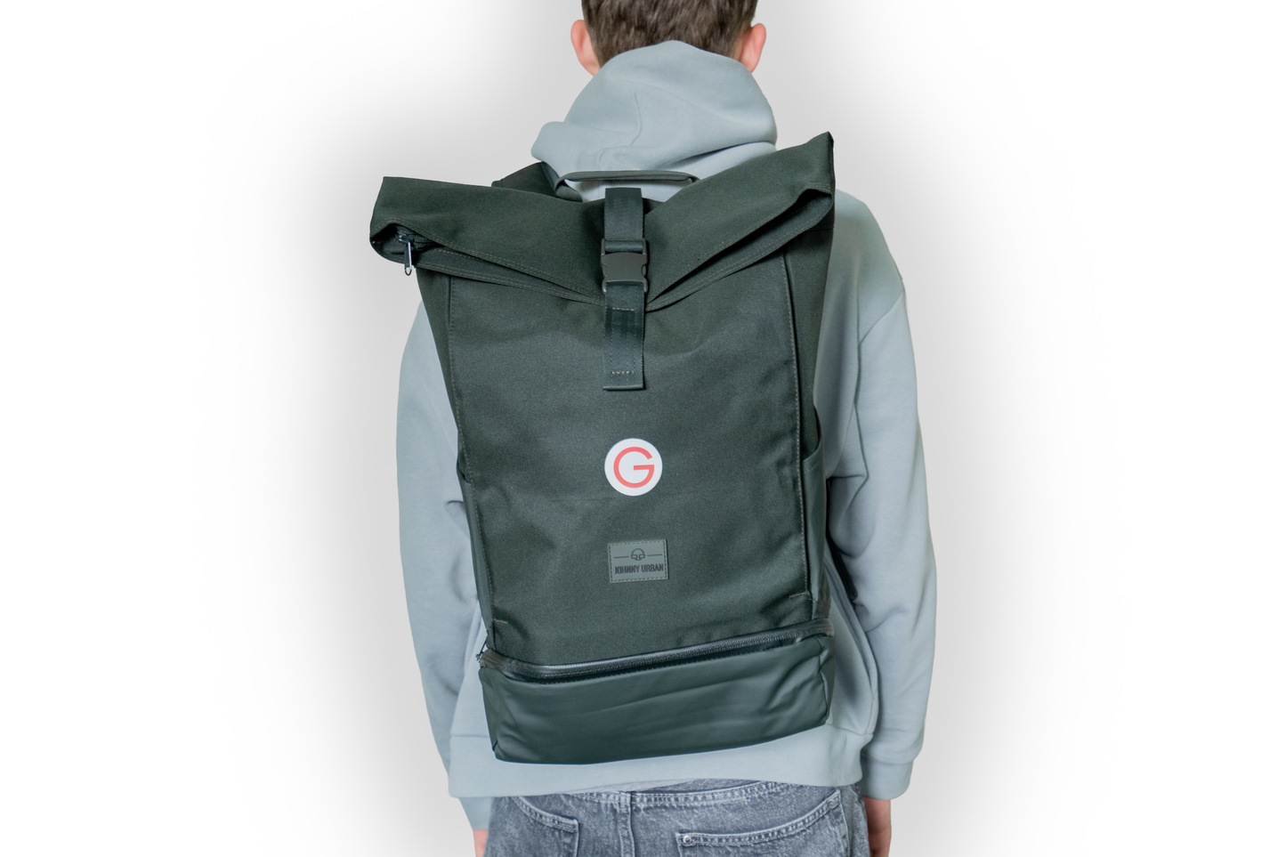 Person, die den dunkelgrünen Rucksack mit kleinem, roten Geiger "G"mit Geiger-Grünem Hintergrund vorne auf dem Rücken trägt