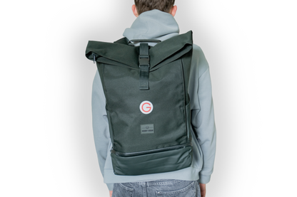 Person, die den dunkelgrünen Rucksack mit kleinem, roten Geiger "G"mit Geiger-Grünem Hintergrund vorne auf dem Rücken trägt