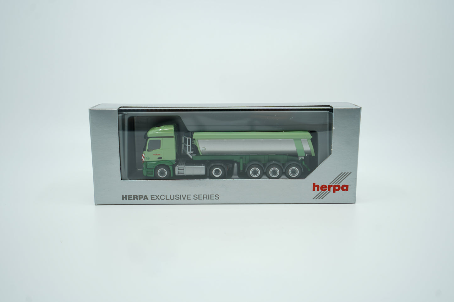 Miniaturmodell eines Mercedes Geiger-LKW in Geiger-Grün mit grauem Thermomulden Anhänger mit rotem "Geiger" Schriftzug. Verpackung inklusive.
