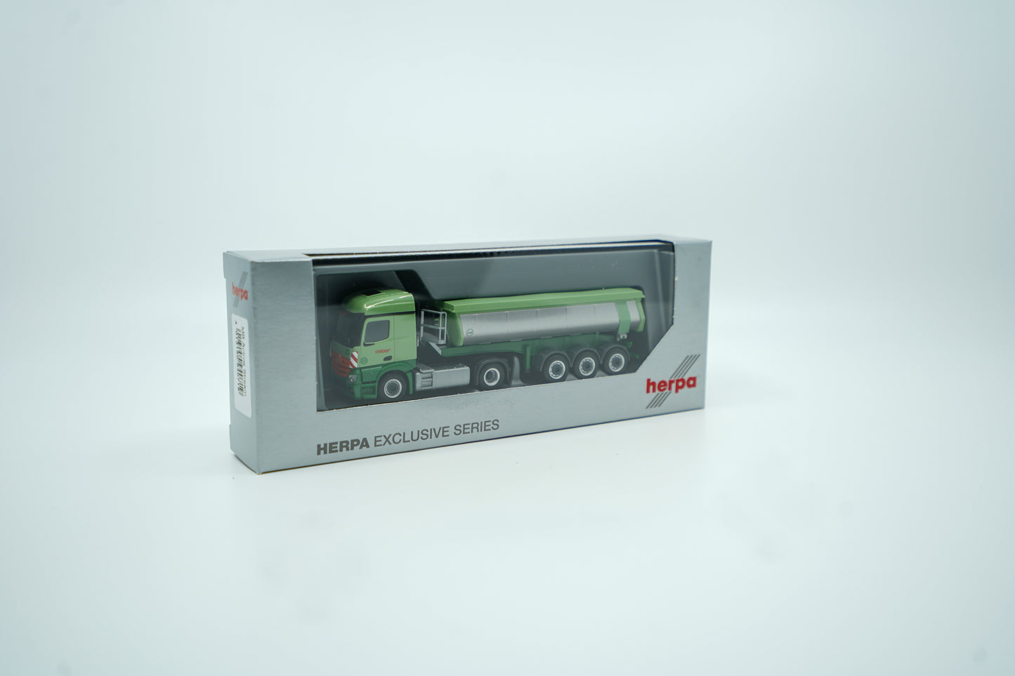 Miniaturmodell eines Mercedes Geiger-LKW in Geiger-Grün mit grauem Thermomulden Anhänger mit rotem "Geiger" Schriftzug. Verpackung inklusive.