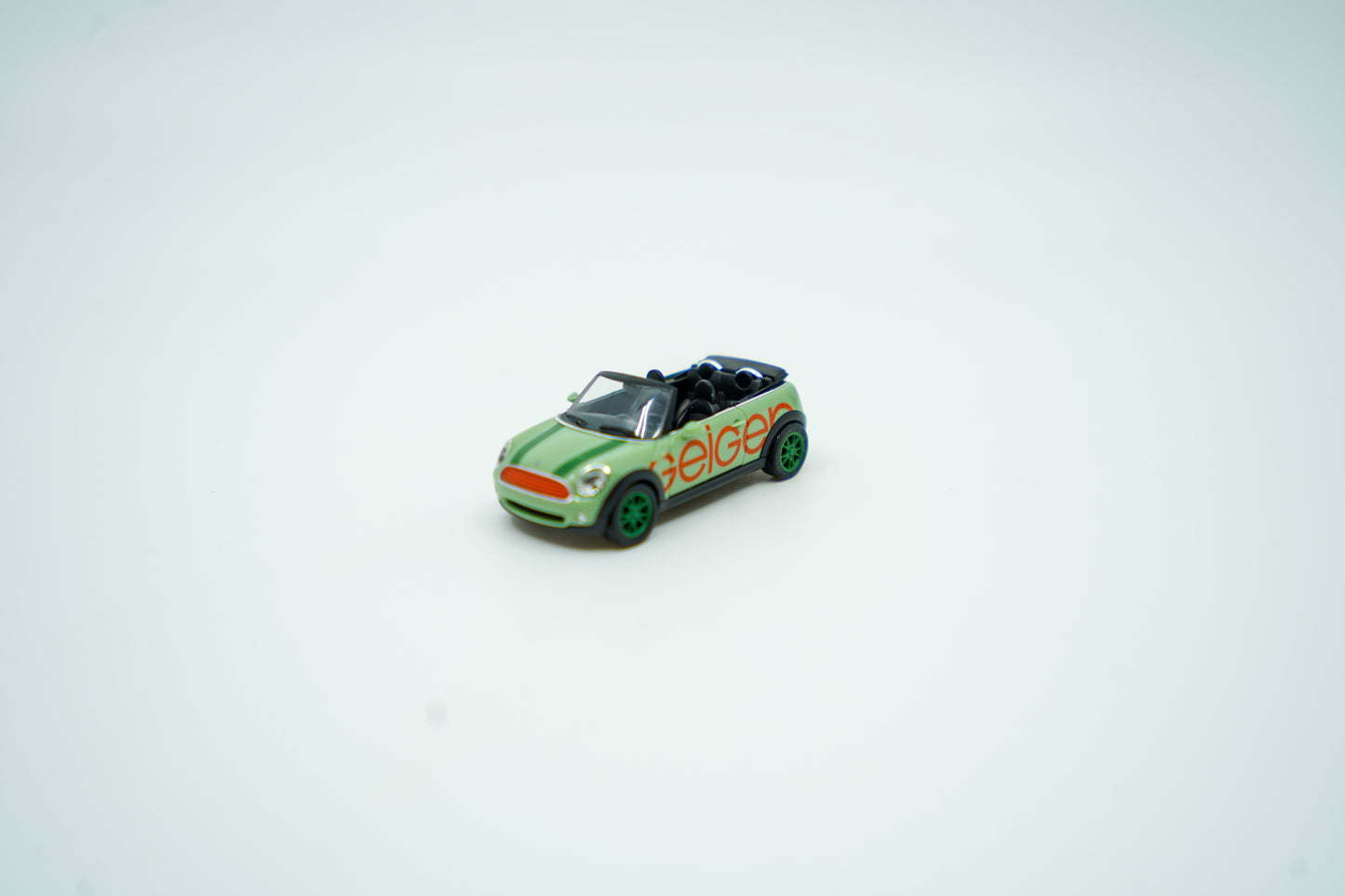 Miniaturmodell eines Geiger Mini-Cooper PKW in Geiger-Grün mit rotem „Geiger“-Schriftzug, Verpackung inklusive.