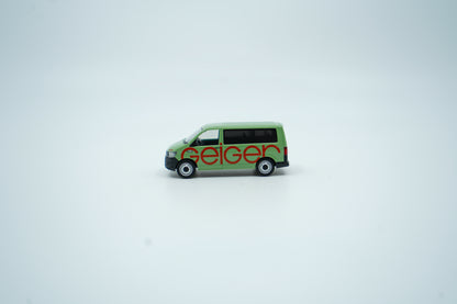 Miniaturmodell eines Geiger VW-Bus in Geiger-Grün mit rotem „Geiger“-Schriftzug, Verpackung inklusive.