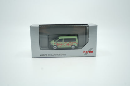 Miniaturmodell eines Geiger VW-Bus in Geiger-Grün mit rotem „Geiger“-Schriftzug, Verpackung inklusive.