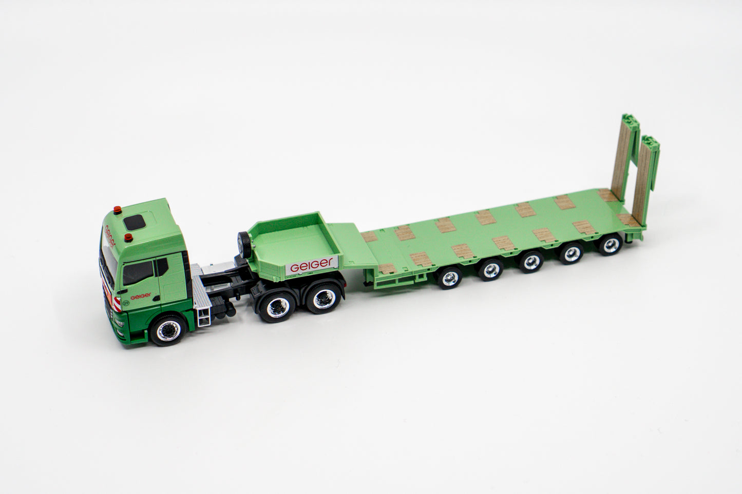 Miniaturmodell eines Geiger MAN TGX GM Thermomulden-Sattelzug in Geiger-Grün mit rotem „Geiger“-Schriftzug.