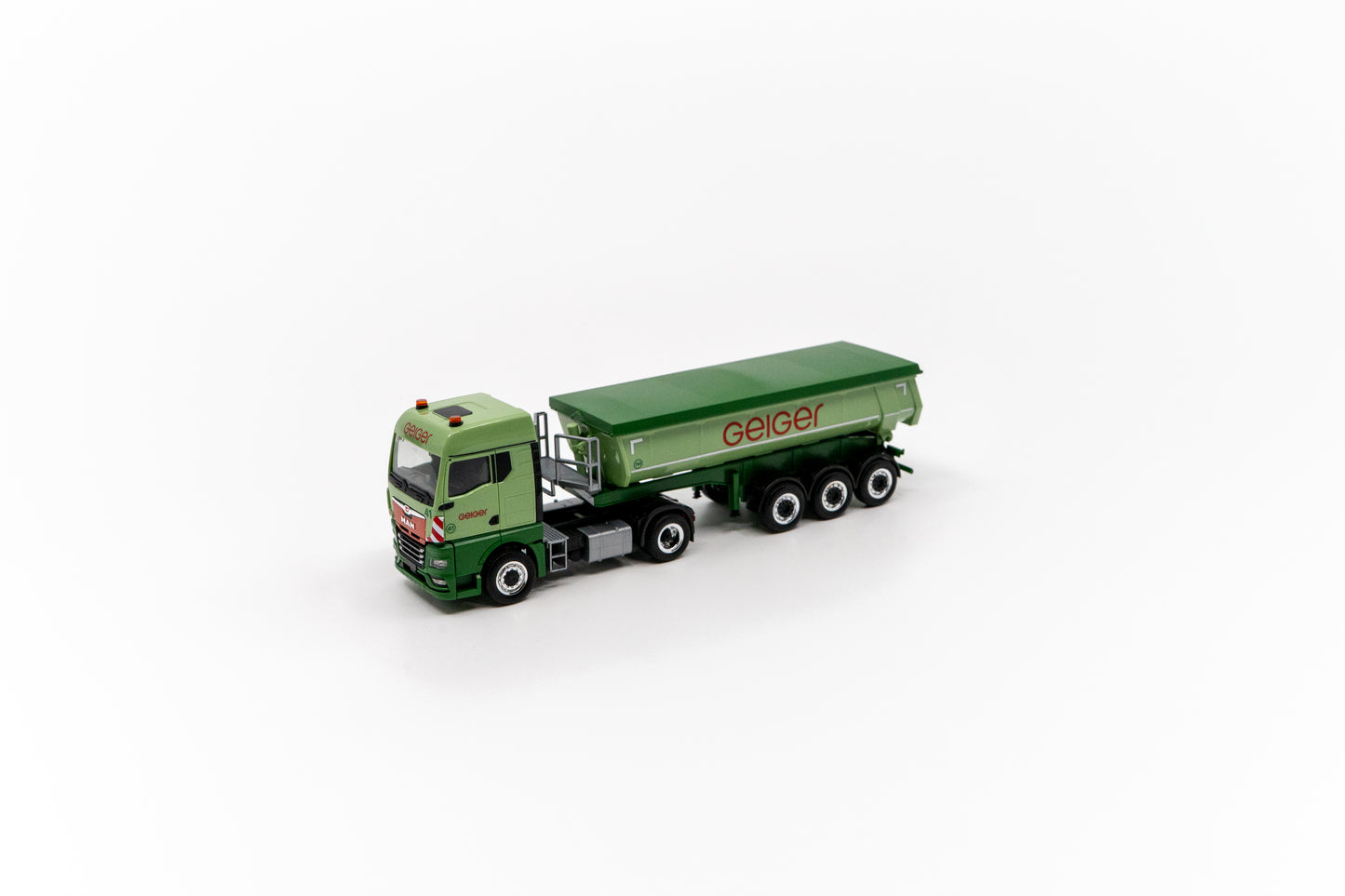 Miniaturmodell eines Geiger MAN TGX GM Thermomulden-Sattelzug in Geiger-Grün mit rotem „Geiger“-Schriftzug.