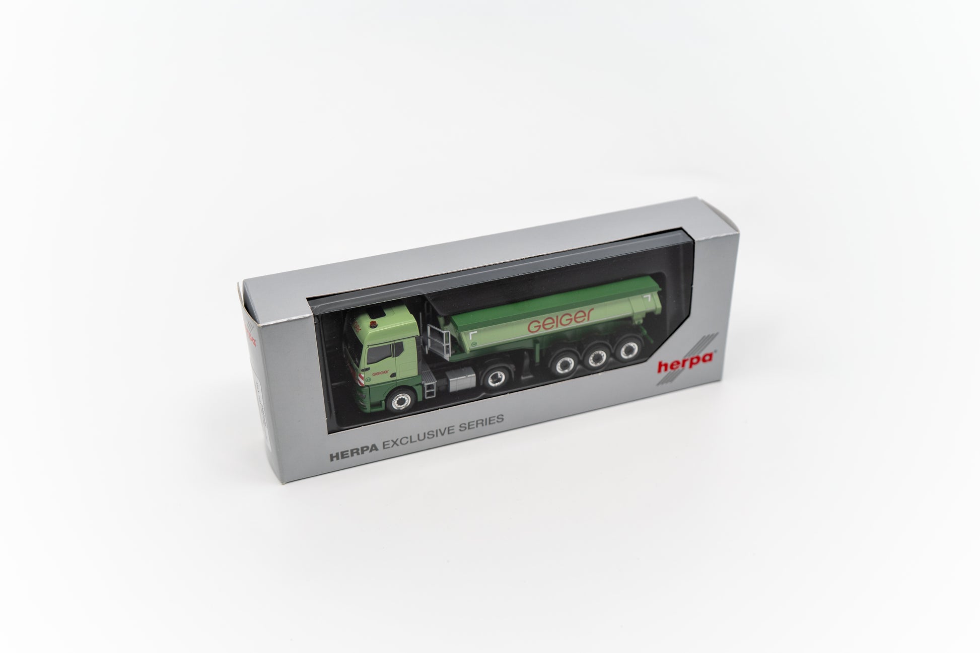 Miniaturmodell eines Geiger MAN TGX GM Thermomulden-Sattelzug in Geiger-Grün mit rotem „Geiger“-Schriftzug.