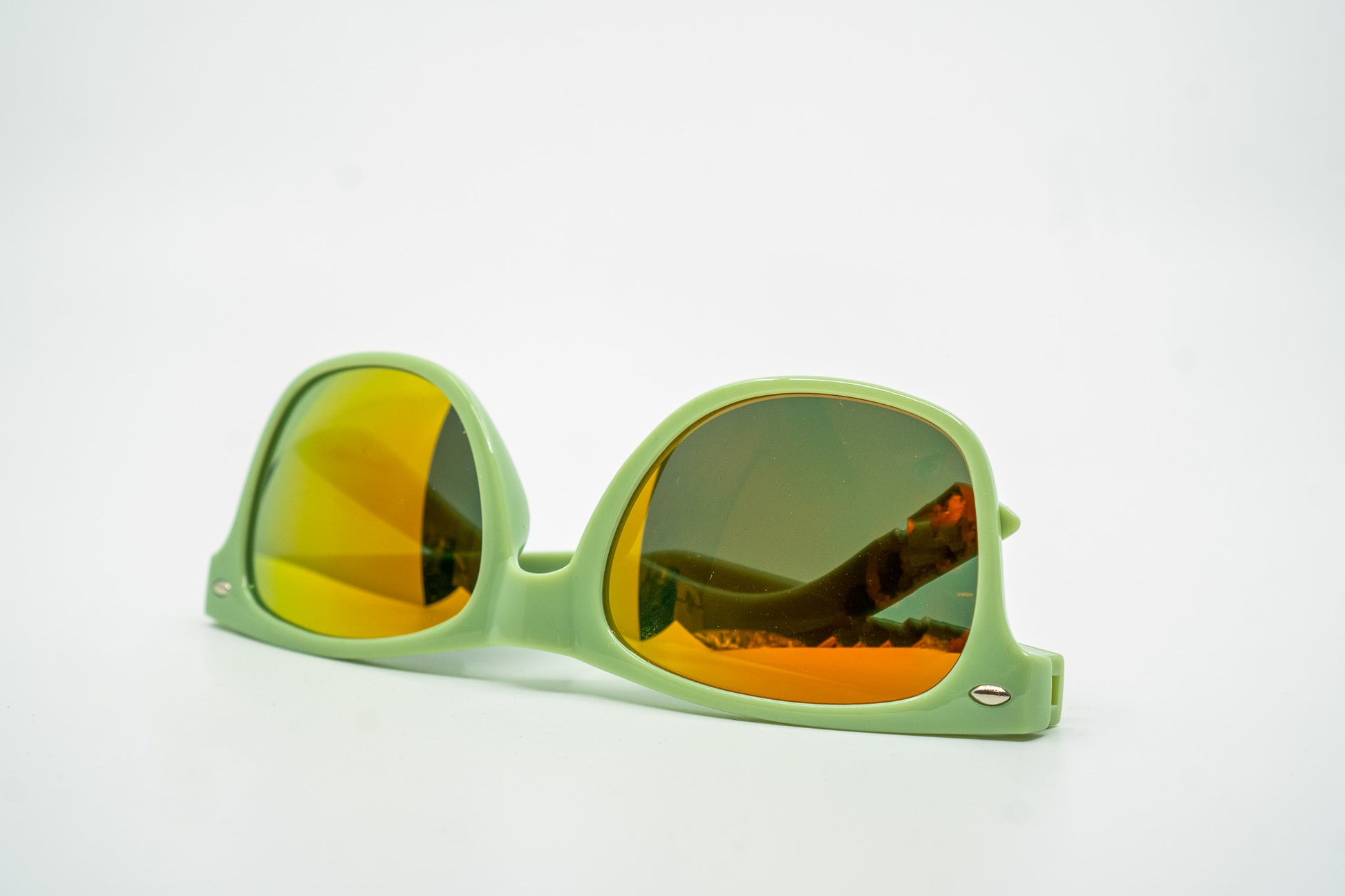 Sonnenbrille in Geiger-Grün mit roten „Geiger“-Schriftzügen an den Bügeln und verspiegelten Gläsern.